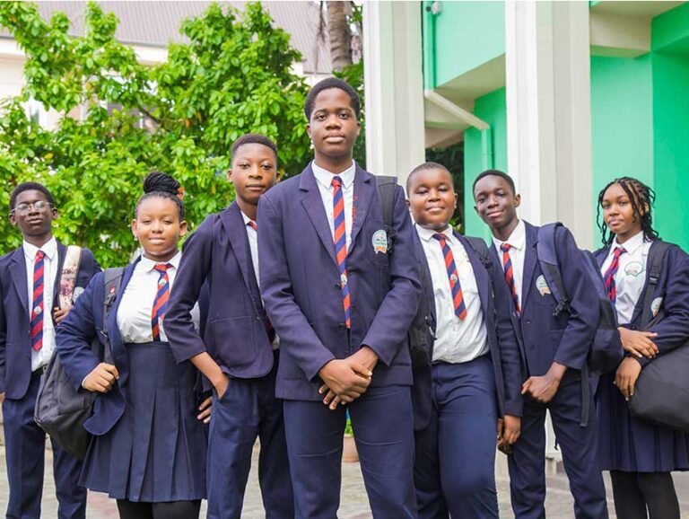 Early Spring College students in navy blazers and striped ties standing together outside the school building