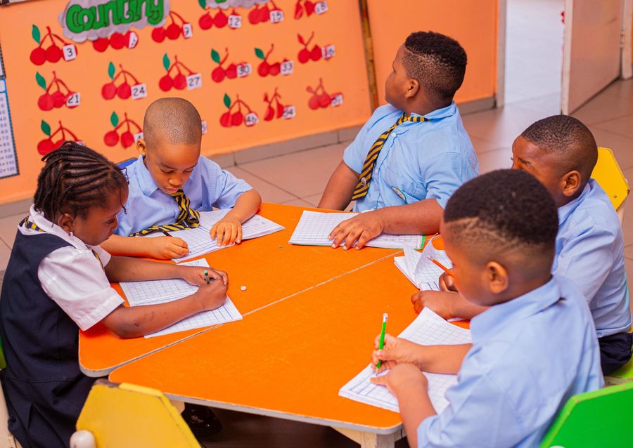 Elementary pupils writing at a shared classroom table