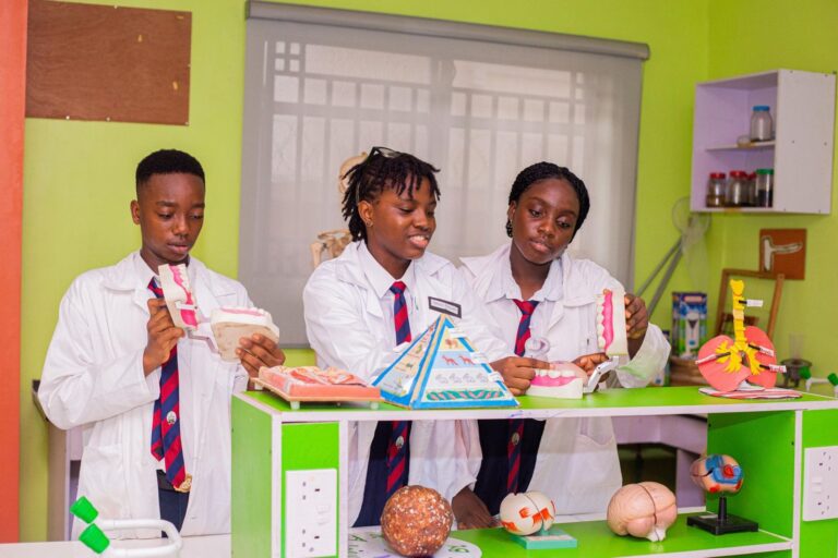 Students in lab coats presenting anatomy and science models