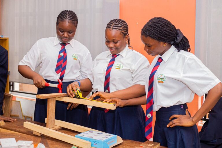 College girls measuring and assembling a wooden frame in the workshop